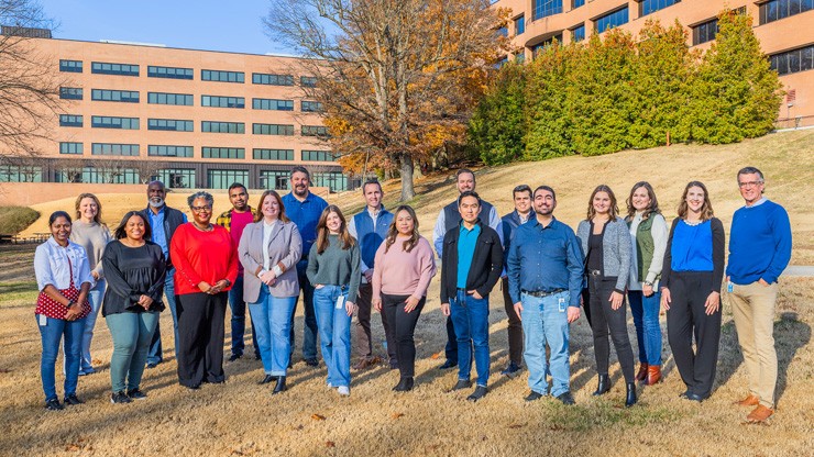 a group of j.b. hunt employees post for a picture outside of the company's headquarters