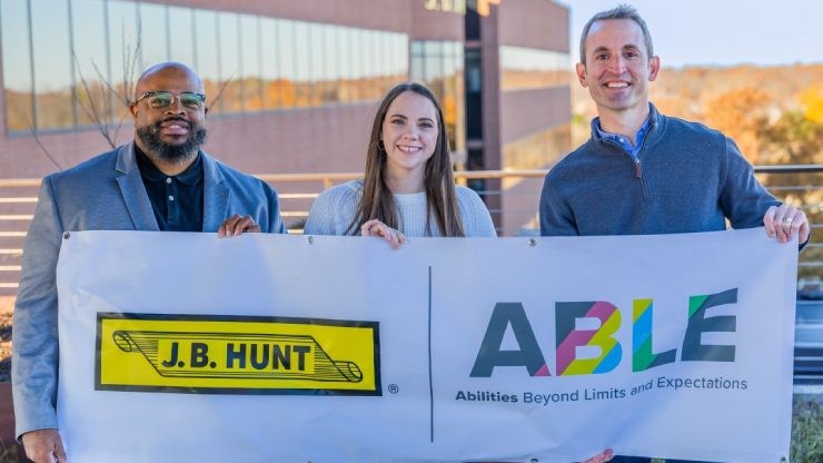 Three ABLE ERG board members holding a banner displaying the J.B. Hunt logo and ABLE slogan “Abilities Beyond Limits and Expectations” outside company headquarters.