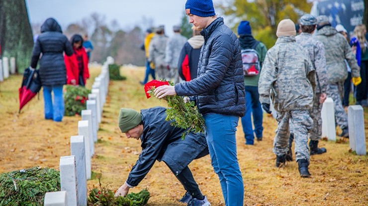 Two boys place wreaths on headstones at the National Cemetery in Fayetteville