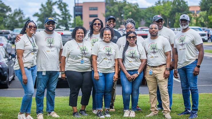 Members of AAmERG standing together for a photo in front of the parking lot of the J.B. Hunt corporate campus..