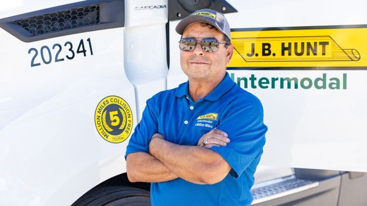 tony the intermodal driver J.B. Hunt Intermodal Driver, Tony, stands in front of truck with arms crossed and smiling