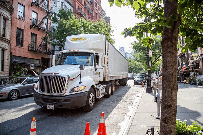 A J.B. Hunt semi truck parks next to orange cones in a New York CIty neighborhood
