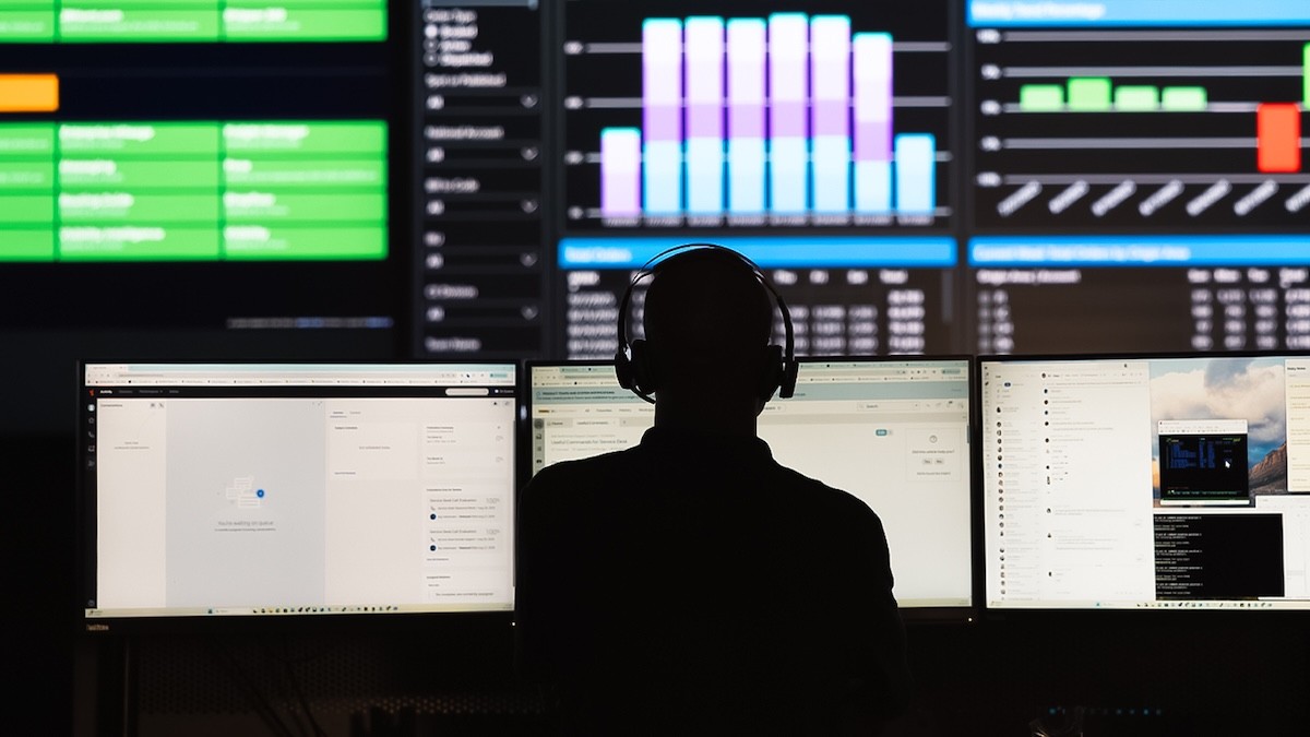 Operations professional monitoring logistics and freight network performance dashboards across multiple computer screens to analyze efficiency and routing data.