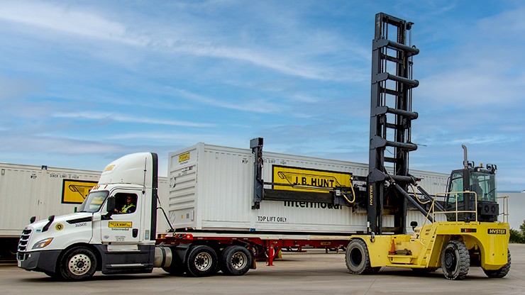 A J.B. Hunt intermodal container is being loaded onto a chassis