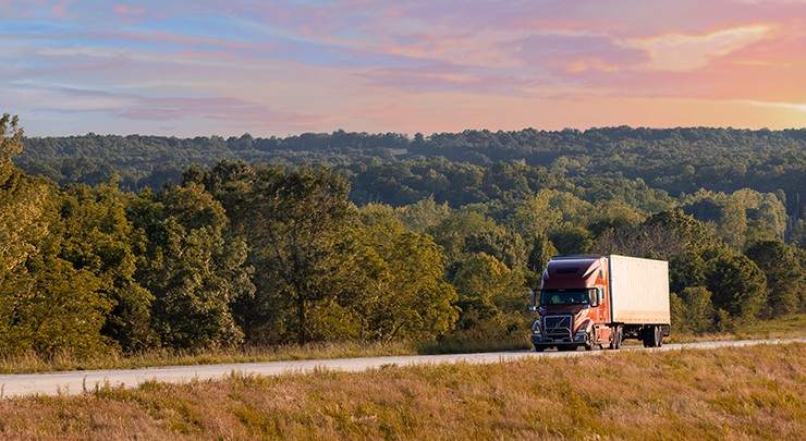 truck driving down a rural highway at sunrise