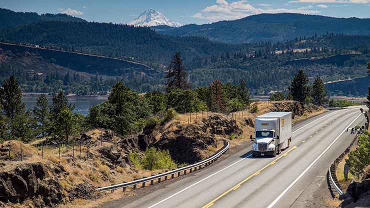 Dedicated J.B. Hunt truck driving on a road with mountains in the background Dedicated J.B. Hunt truck driving on a road with mountains in the background