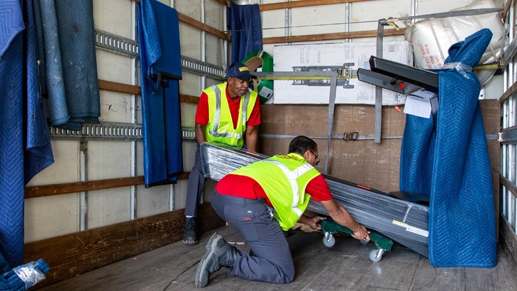 workers getting treadmill of truck