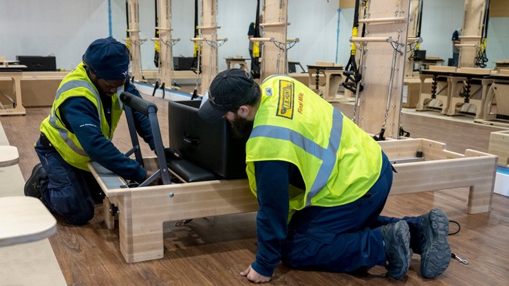 workers setting up rower in fitness space