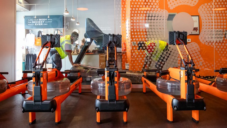 workers wheeling in treadmill with rowers in the foreground