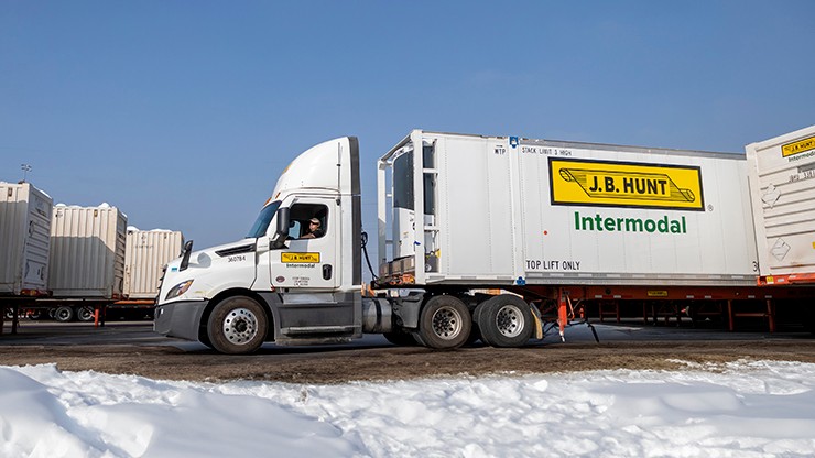 Intermodal TC truck snow A J.B. Hunt temperature-controlled intermodal truck and trailer backing into parking spot in a snowy lot.