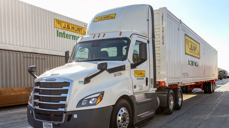 White J.B. Hunt intermodal truck loaded with an intermodal container parks at a loading dock