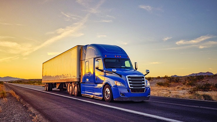 Blue truck driving away from sunset