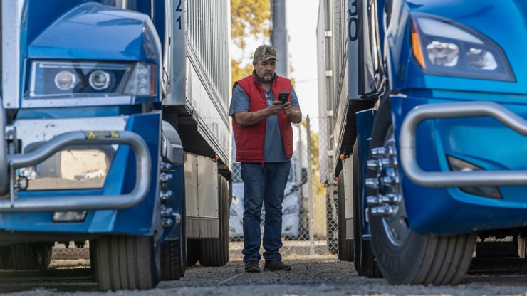 driver checking his carrier app between two truck