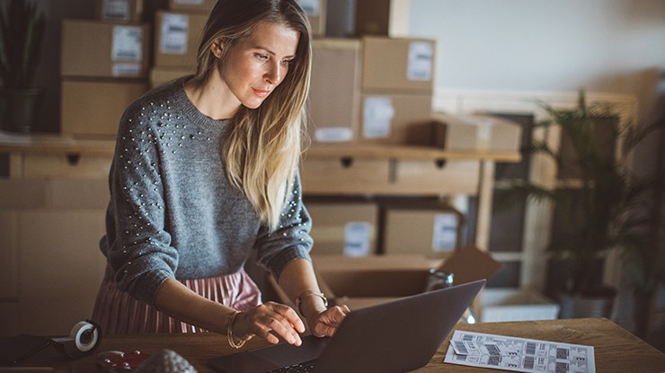 Shipper customer female in grey sweater using a laptop Shipper customer female in grey sweater using a laptop