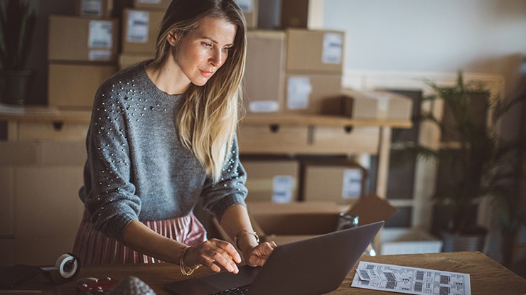 Shipper customer female in grey sweater using a laptop