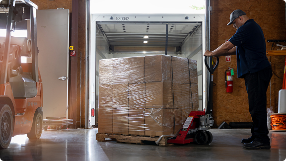 employee moving palette with pallet jack
