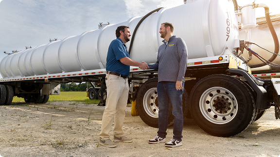 j.b. hunt employee shakes hands with a customer in front of a tanker truck