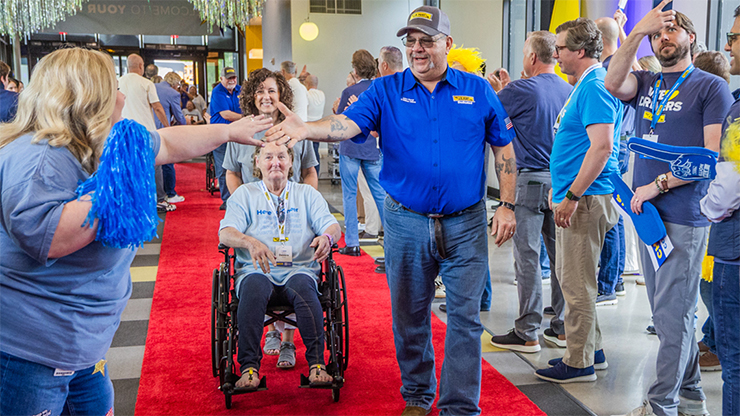 J.B. Hunt employee in blue shirt high-fives supporters as he walks a red carpet, celebrating one million miles of safe driving