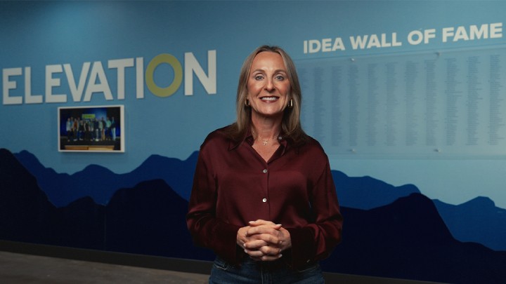 Shelley Simpson Stand in front of Elevation Idea Wall of Fame