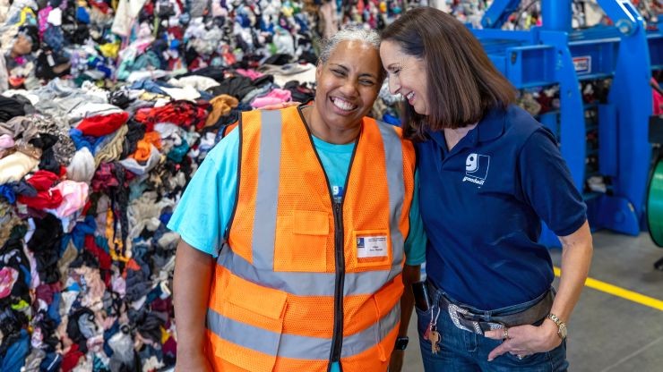 goodwill employee and j.b. hunt employee hugging in front of clothes