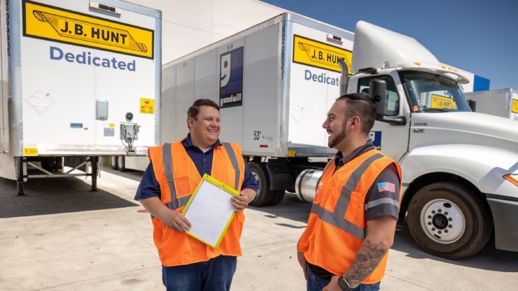 dedicated drivers talking outside of trucks and trailers