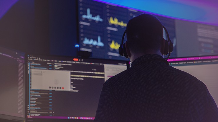noc employee monitoring cargo security using many computer screens in a dark room