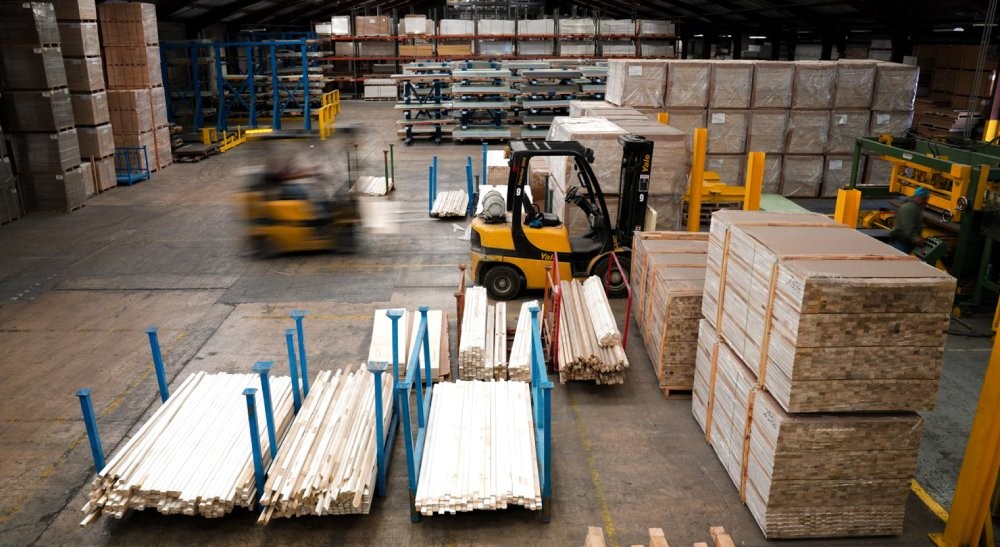lumber in warehouse with forklifts moving things in the background