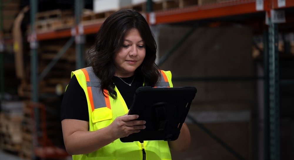 woman in warehouse looking at tablet wearing high vis vest