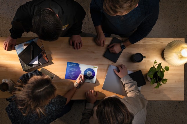 Four people gathered together looking at a document. 