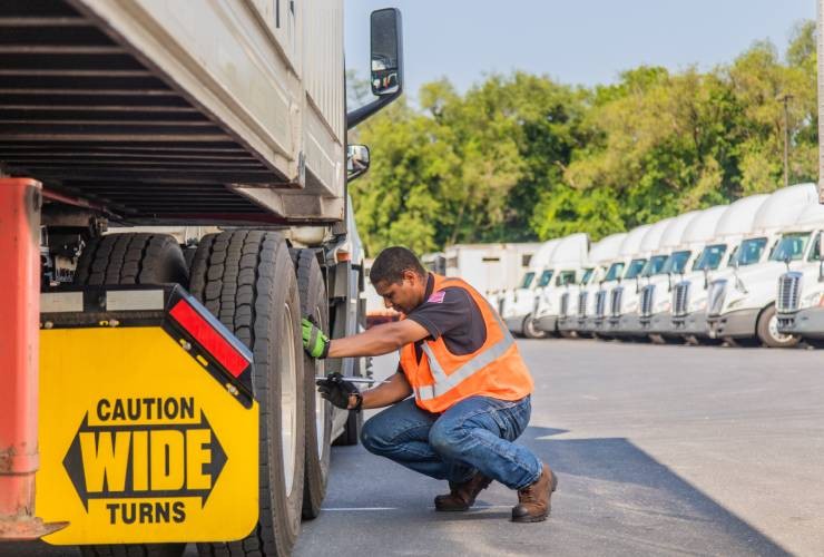 driver checking tires on a trailer