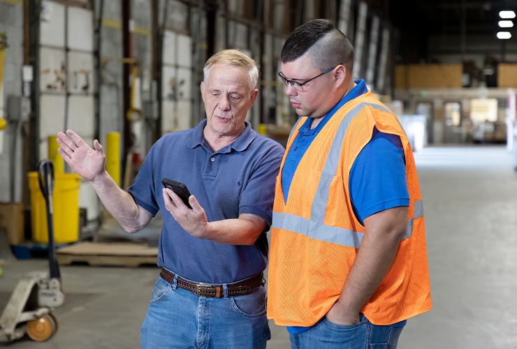 two people look at a cell phone in a loading dock