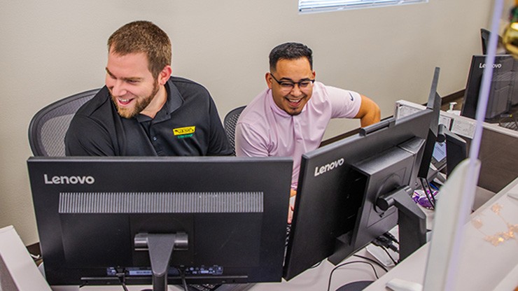  Two J.B. Hunt employees smiling at two computer monitors