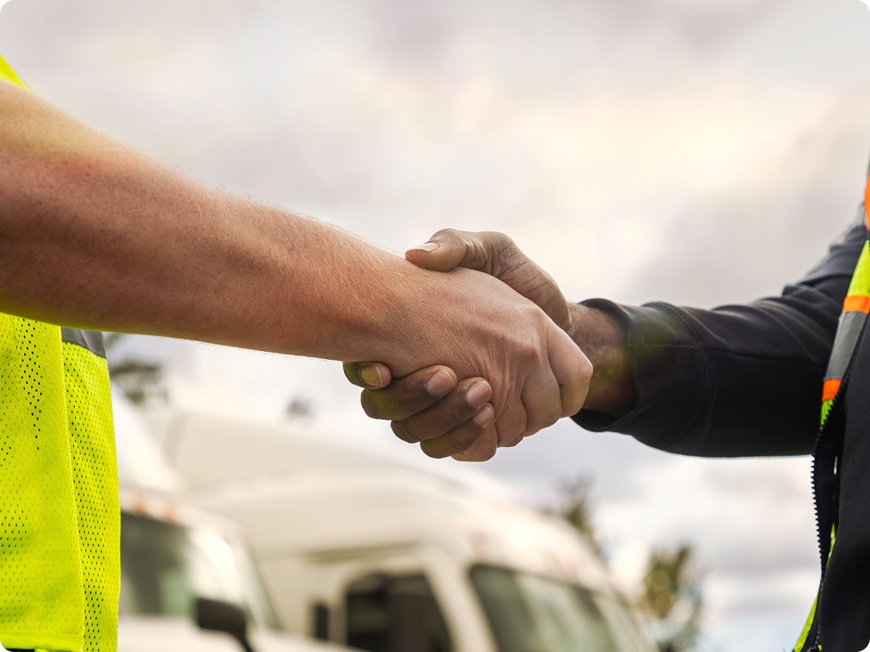 close up of two people shaking hands outside in front trucks