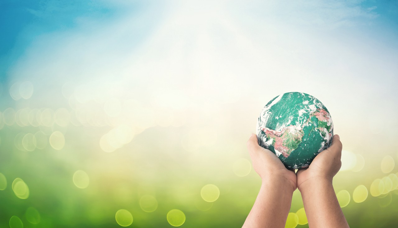Human hands holding earth global on blurred green nature background. Elements of this image furnished by NASA