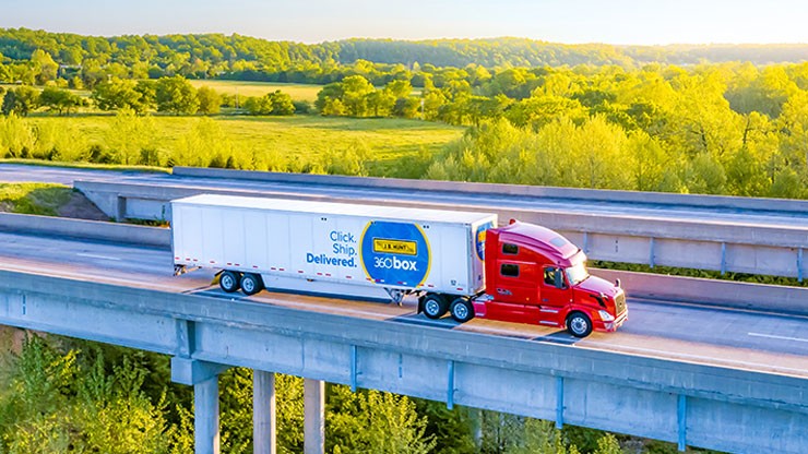 A J.B. Hunt 360box tractor trailer drives over a bridge on a sunny day