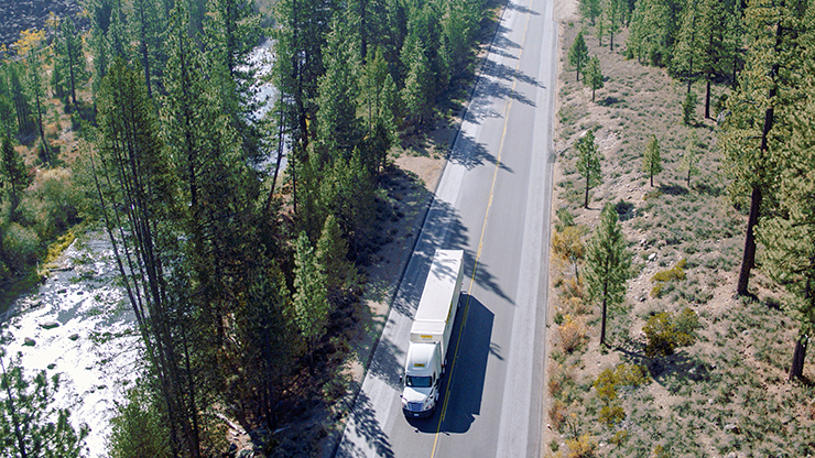 Intermodal truck on highway aerial photo of white J.B. Hunt semi truck and trailer traveling down two lane highway