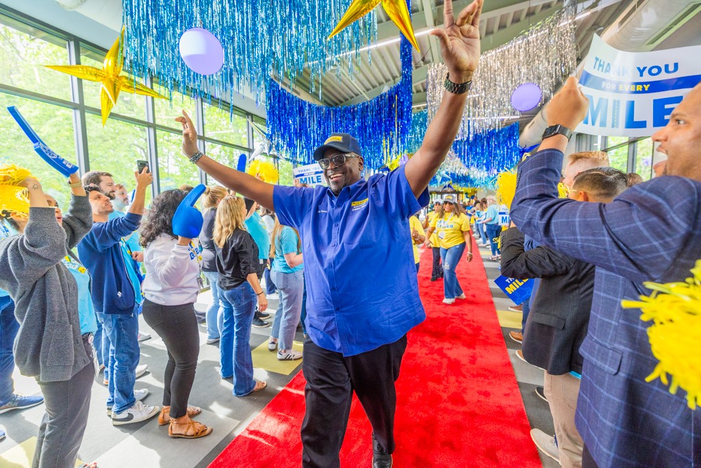 J.B. Hunt Driver with arms up celebrating around crowd walks down the Million Mile walk of fame.