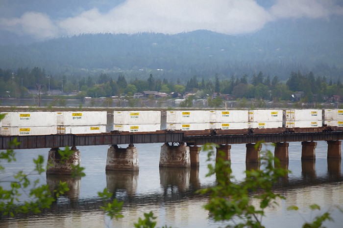photo of J.B. Hunt shipping containers on train cars crossing a bridge over a lake