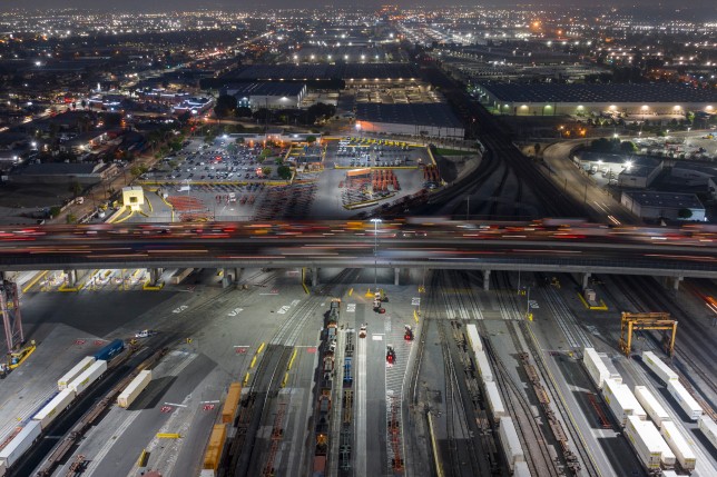 Timelapse of rail yard under a busy highway at night. 
