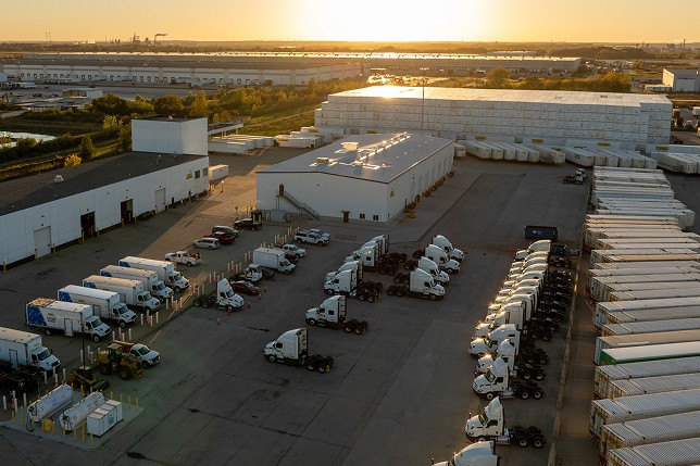  A fleet of tractors and trailers parked at a facility. 