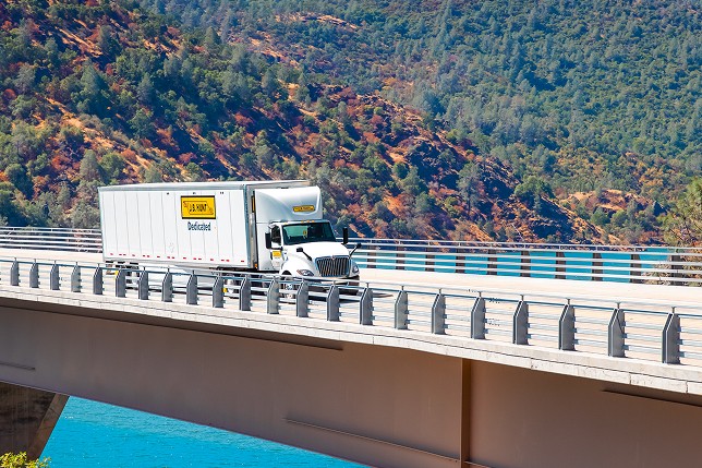 A J.B. Hunt Dedicated Contract Services® truck driving over a bridge. 