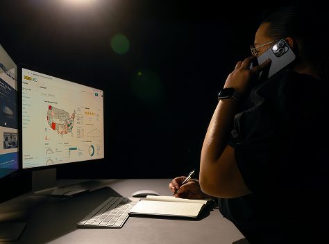 Support person on phone in front of computer monitors