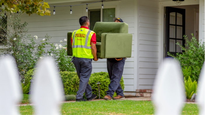 two final mile delivery workers carrying a chair into a house