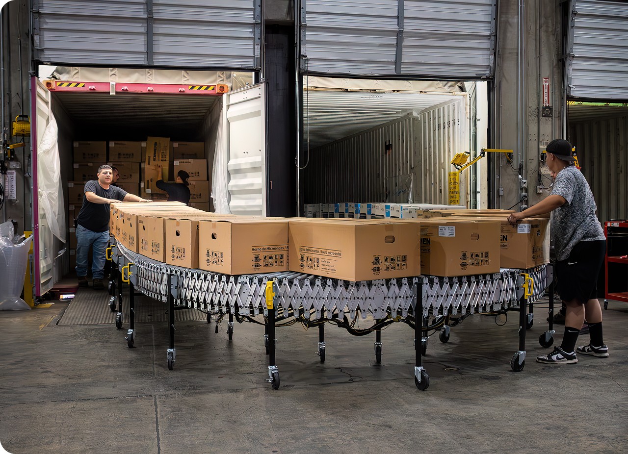 employees using a conveyor to move freight from one container to another