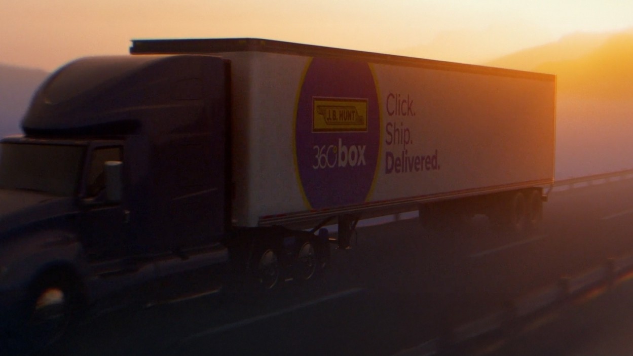Semi truck with trailer driving down a mountain pass highway with a J.B. Hunt 360box logo on the side at dusk