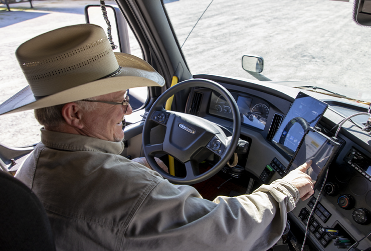 carrier wearing a cowboy hat using the app on an ipad inside of a truck