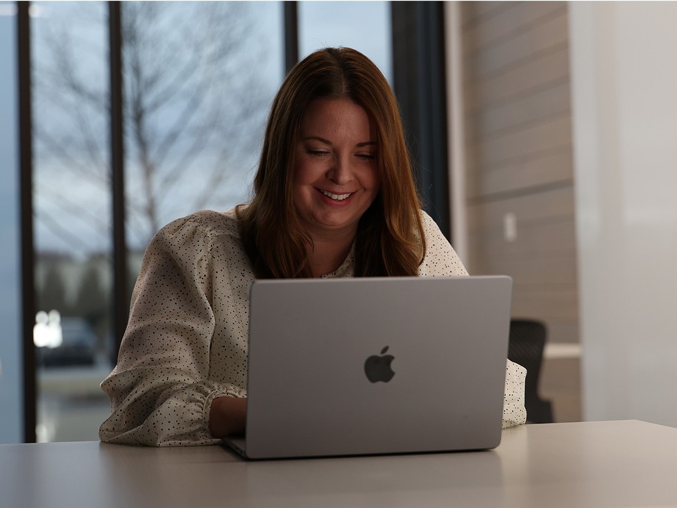A J.B. Hunt corporate employee smiling while working on their laptop