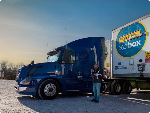 Driver using phone next to truck with 360box trailer